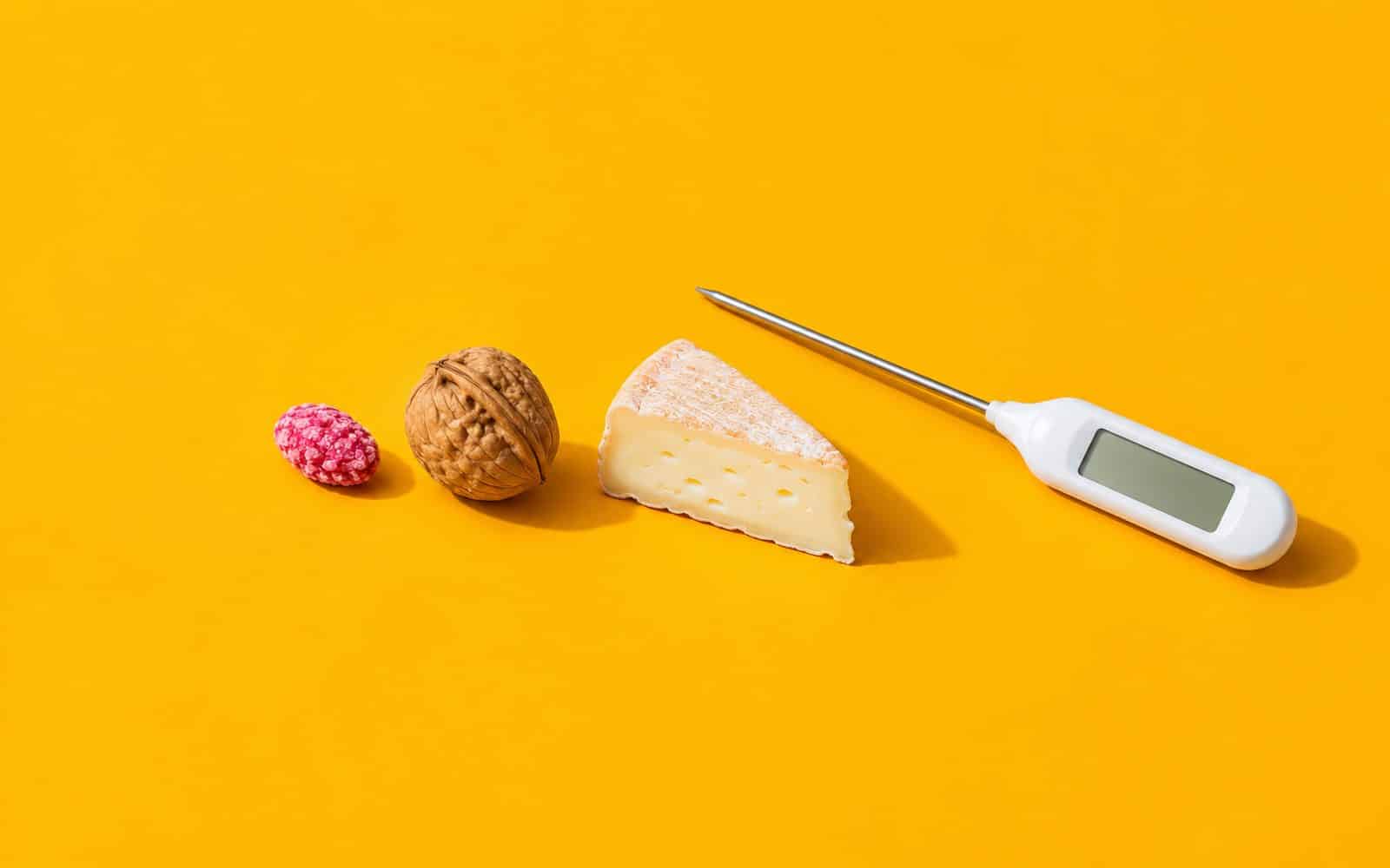 Praline rose, noix, part de fromage et thermomètre à sonde alignés