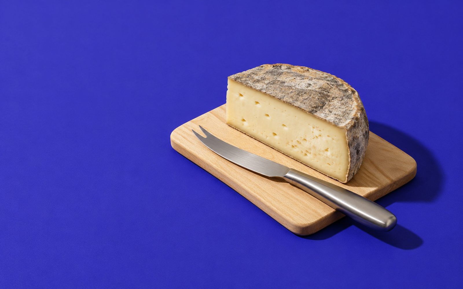 Demi-meule de saint-nectaire sur planche en bois avec couteau à fromage