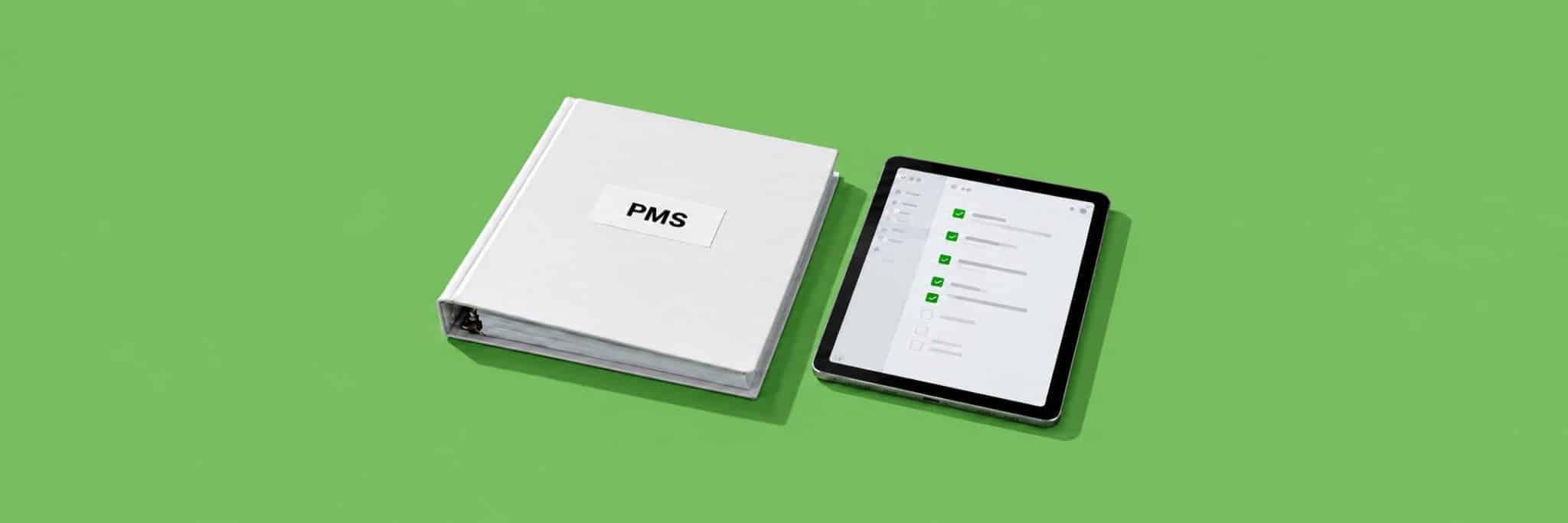 Classeur blanc étiqueté PMS posé à côté d'une tablette qui affiche une liste de contrôle cochée, sur un fond vert